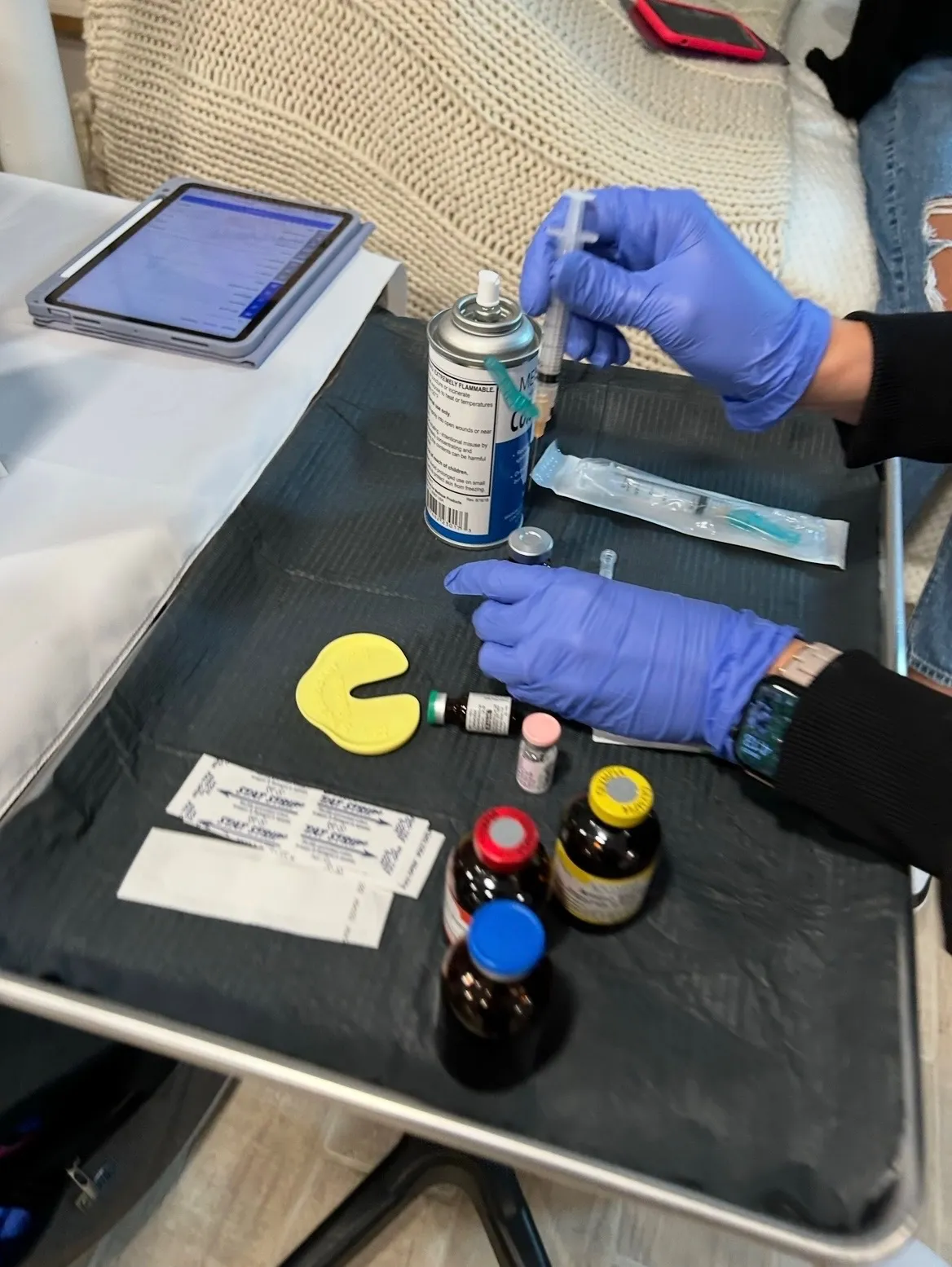 Gloved hands preparing a syringe over the visit tray in a client's home